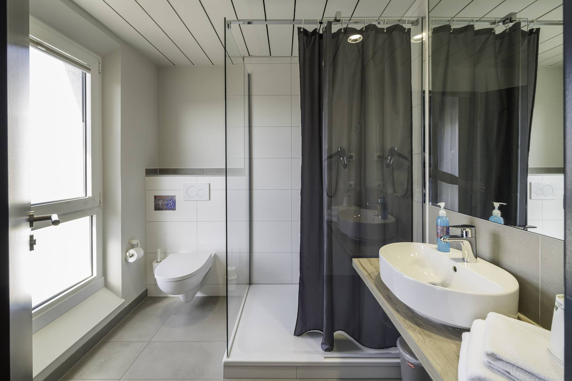 Badezimmer des WIROtels mit bodengleicher Dusche, WC und Waschbecken