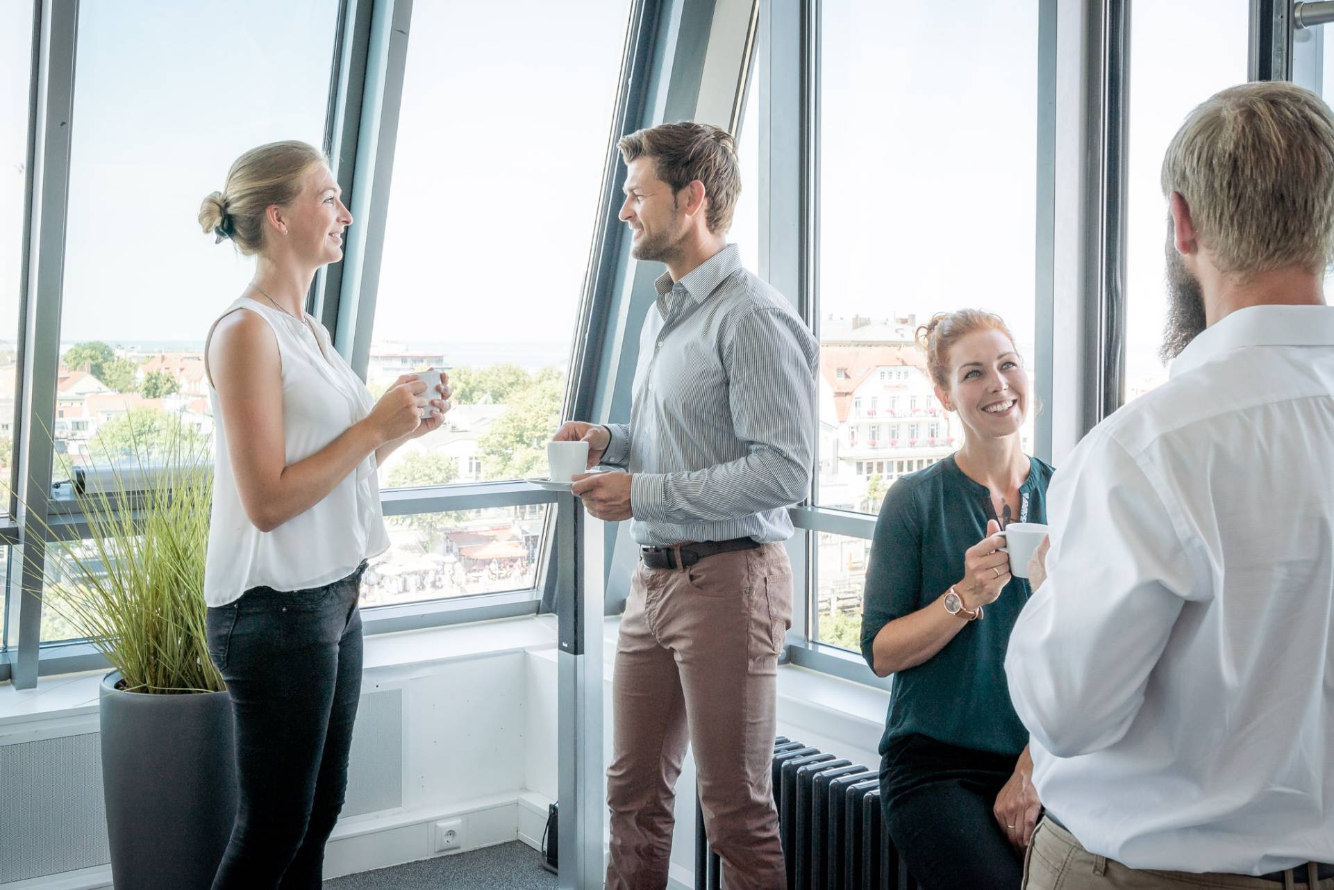 Konferenzteilnehmer:innen stehen am Fenster und unterhalten sich bei Getränken