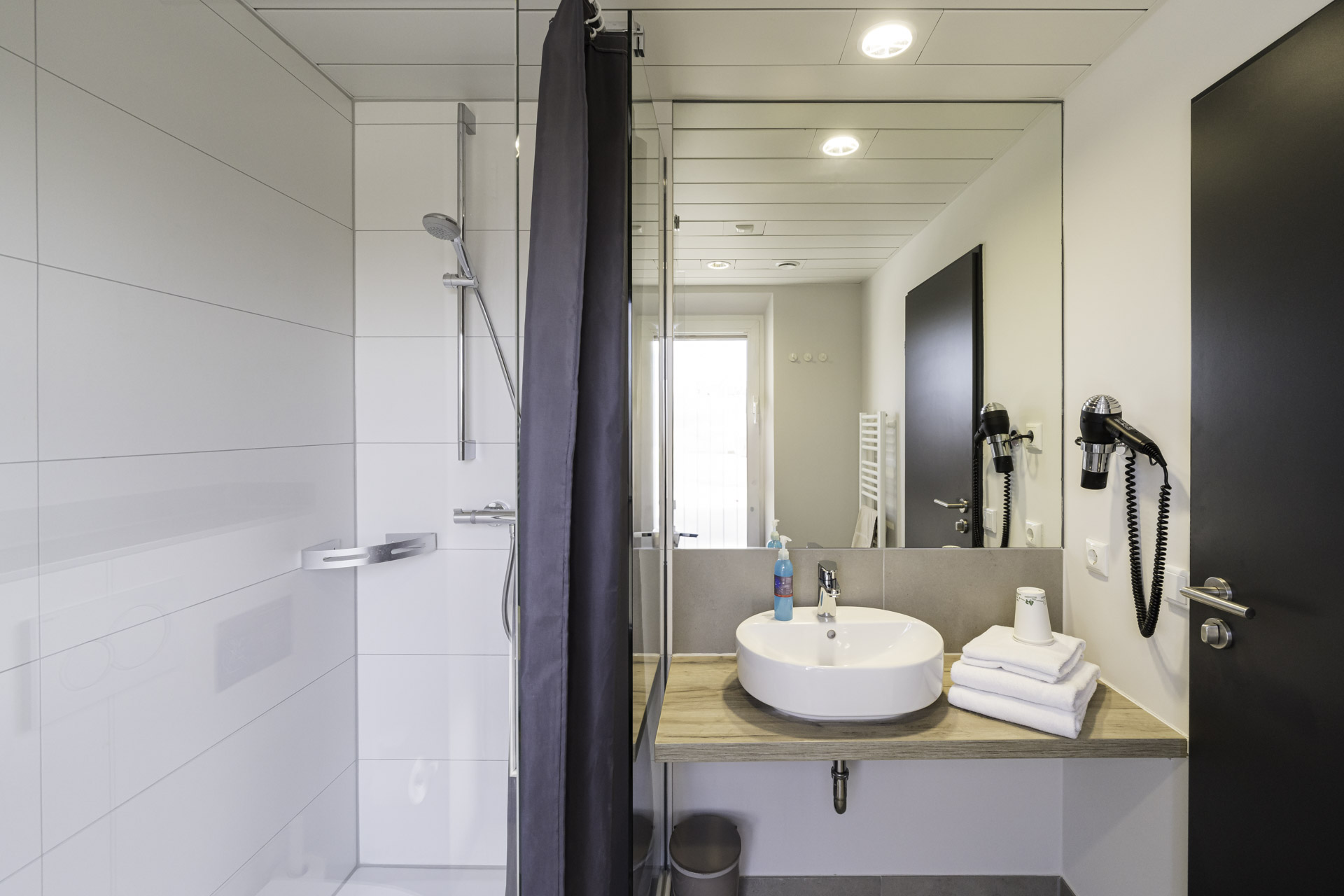 Badezimmer eines Vierbettzimmers mit Dusche, Waschbecken und WC