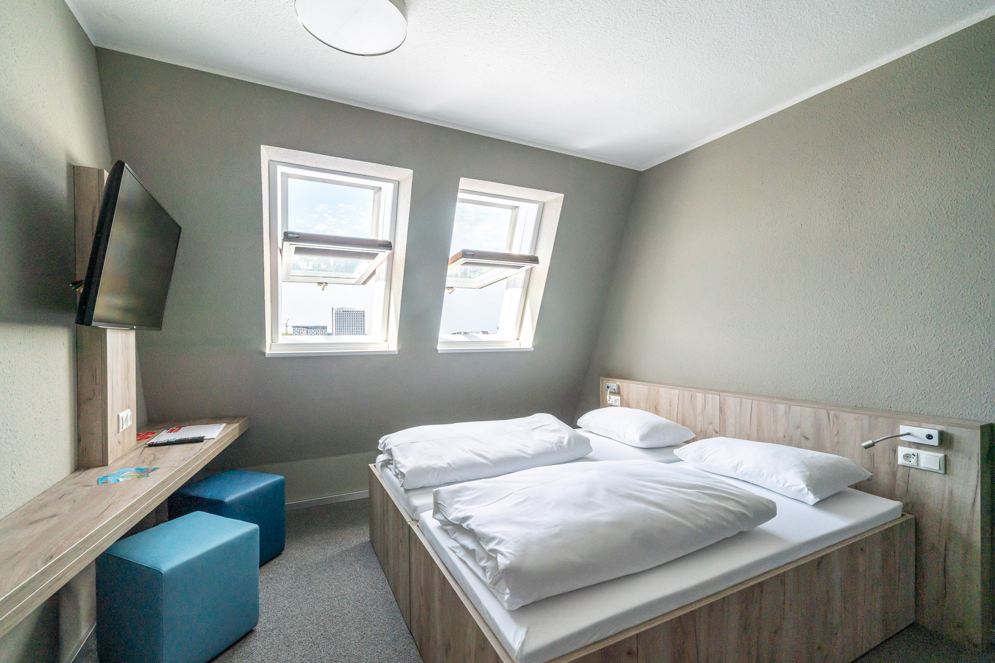 Doppelzimmer des WIROtels mit Doppelbett, zwei Dachfenstern und Sitzbereich