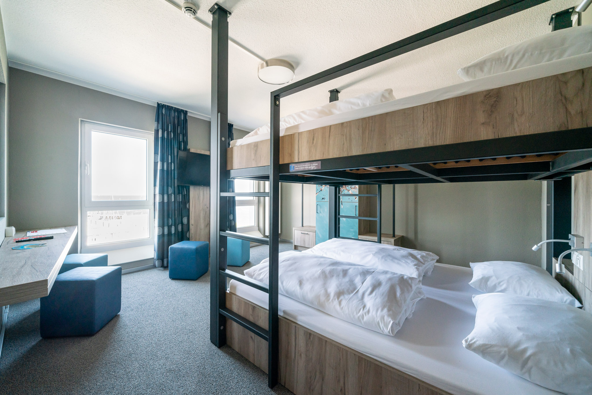 Vierbettzimmer des WIROtels mit zwei Etagenbetten und Sitzbereich am Fenster