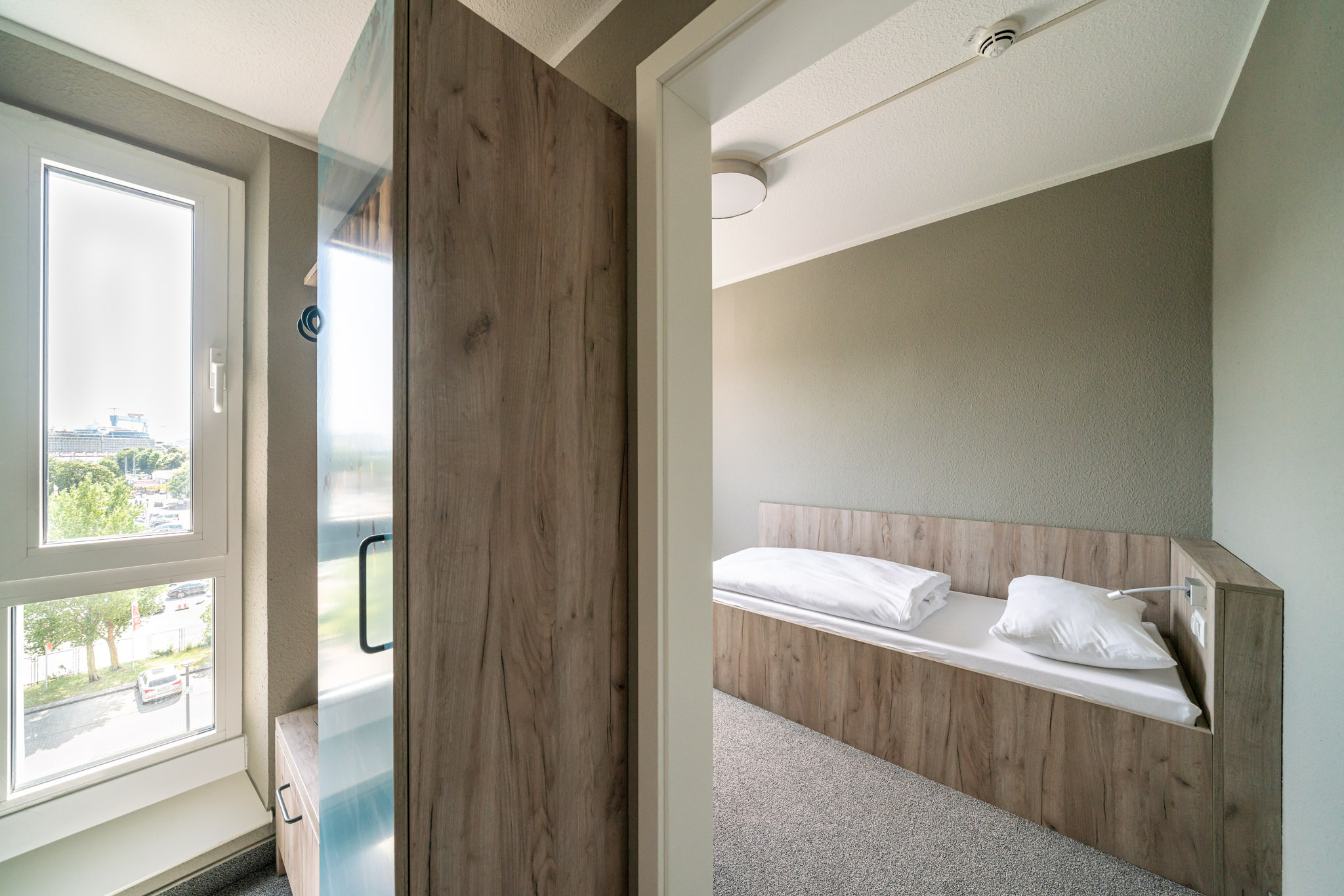 Blick vom Eingangsbereich in ein Einzelzimmer mit Bett und offenem Kleiderschrank